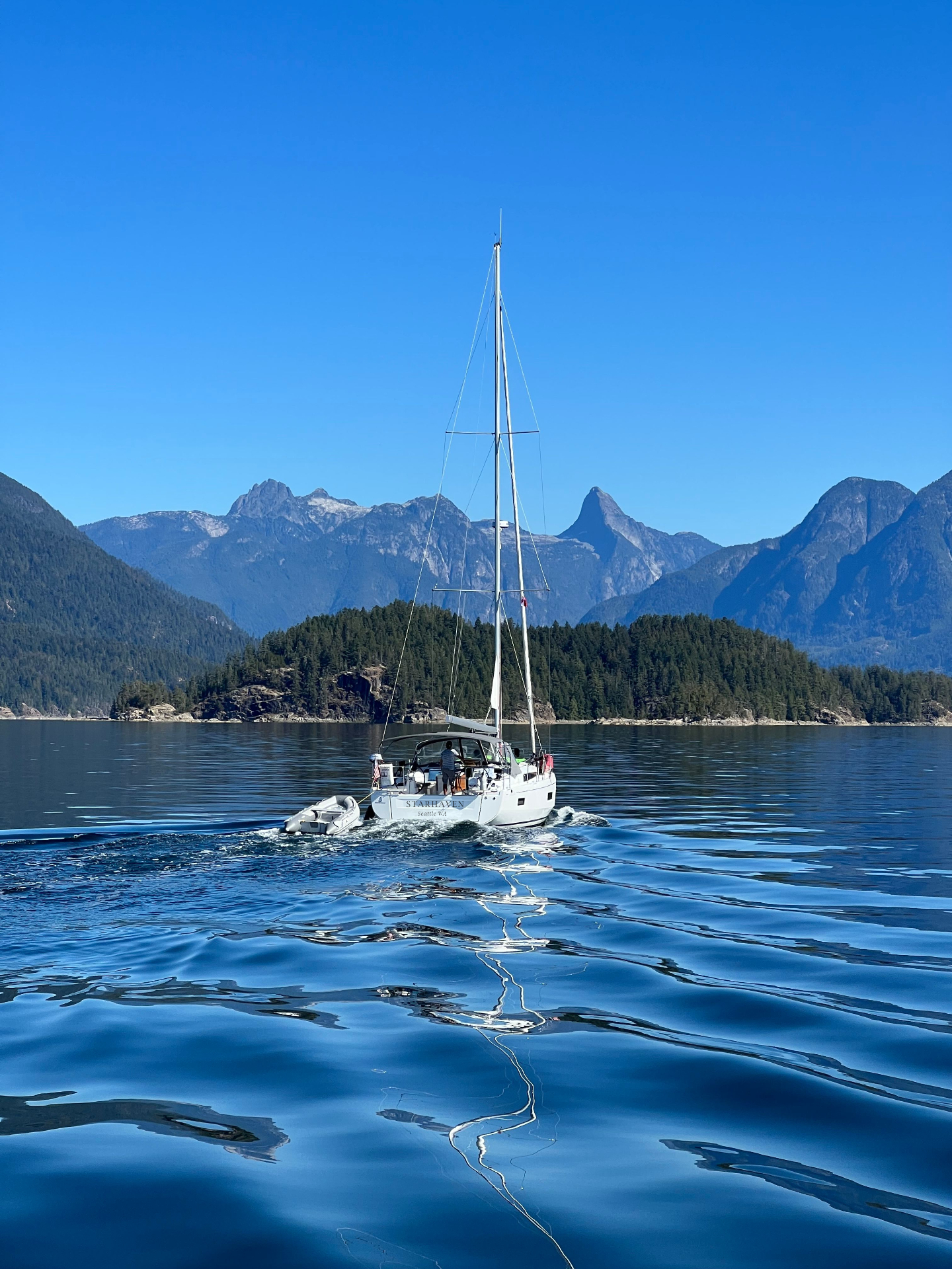 Sailboat under sail on the Salish Sea with Pacific Northwest mountains behind